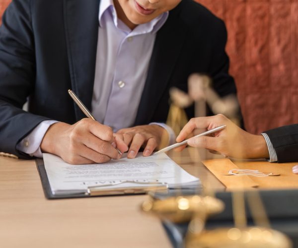 A lawyer assists a client in signing a legal contract, demonstrating attention to detail and clarity in legal procedures within a contemporary office environment.